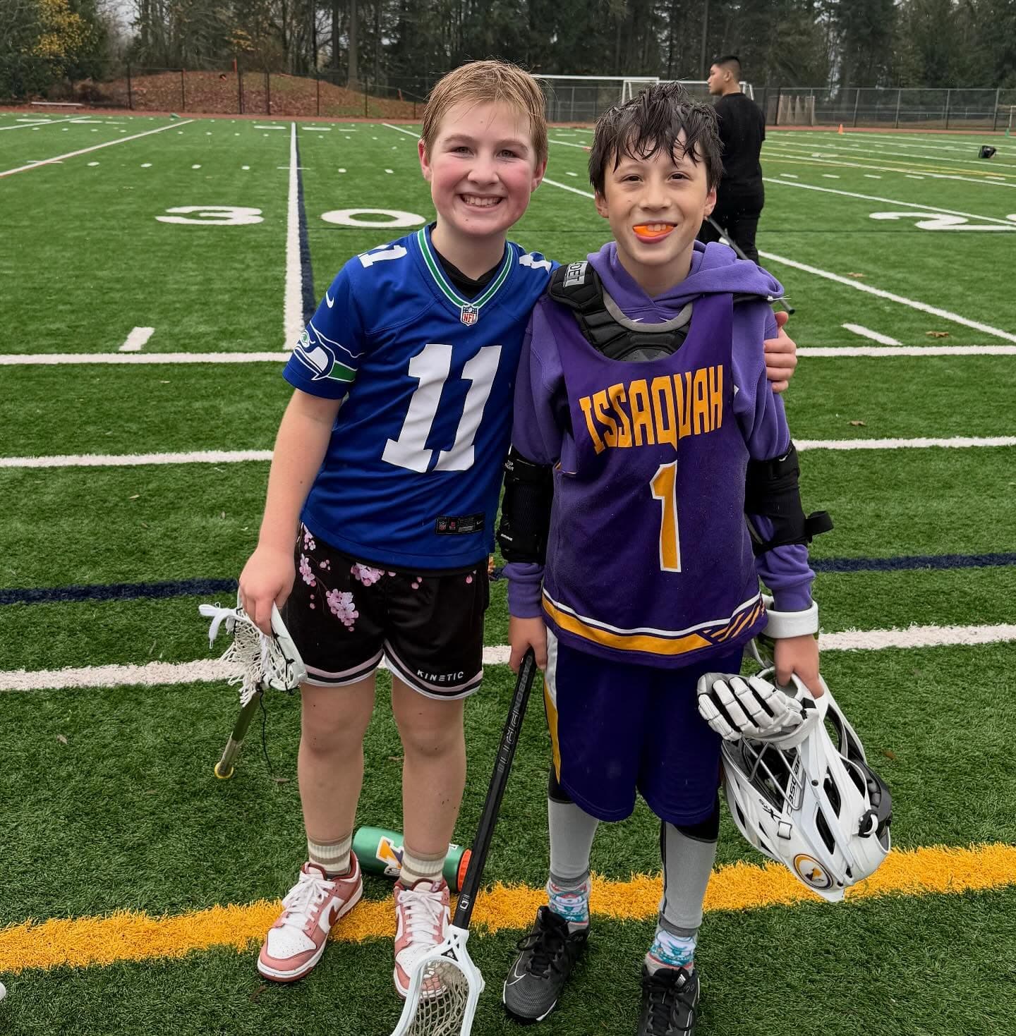 Two smiling friends with lacrosse sticks at the club’s 2025 Bring-a-Friend practice.