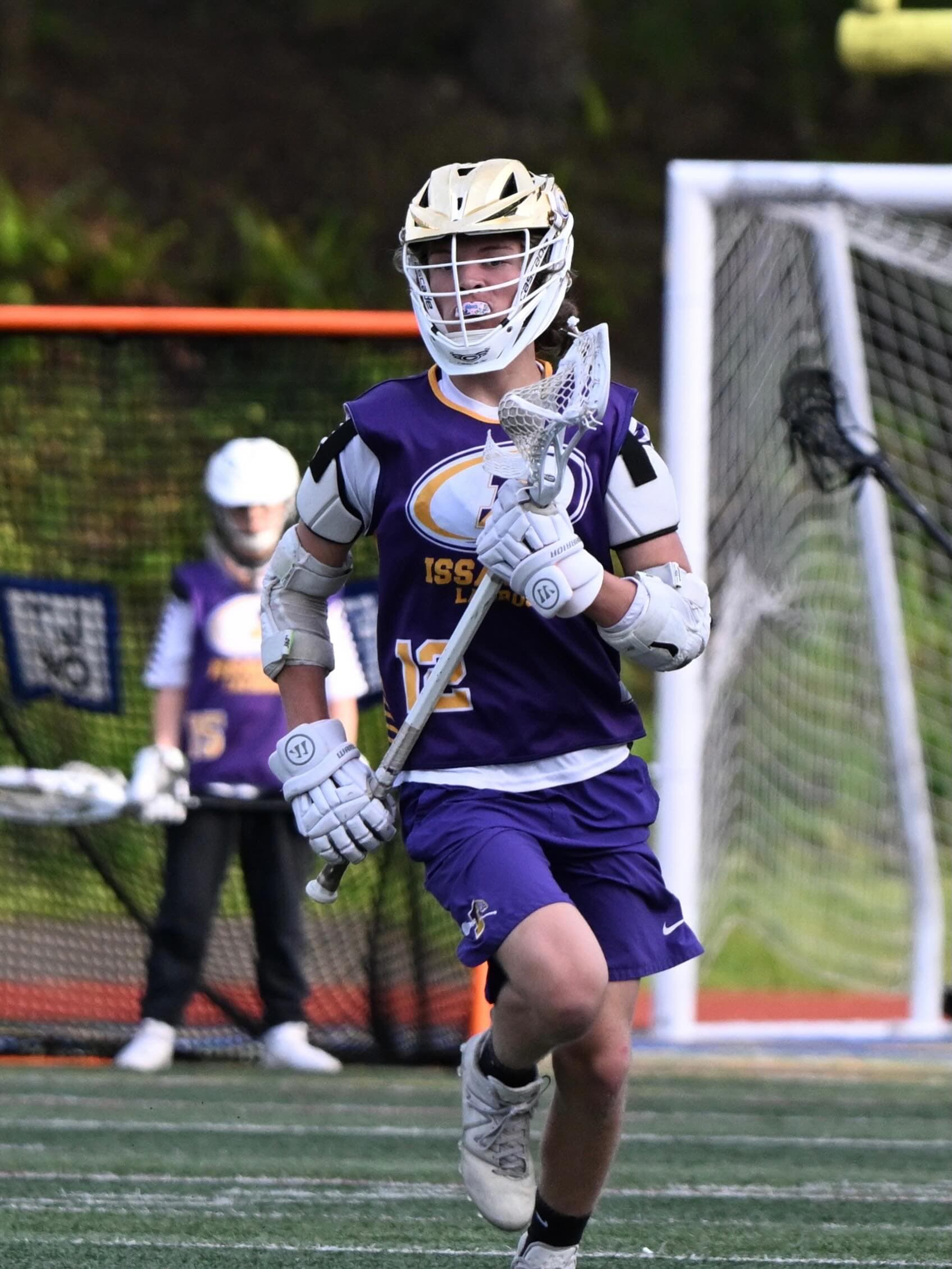 An Issaquah 7/8 player carrying his lacrosse stick on the field.