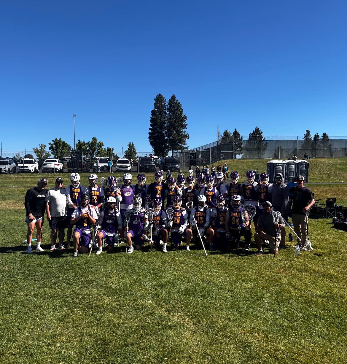 Issaquah high-school lacrosse players and coaches together on the field in Bend.