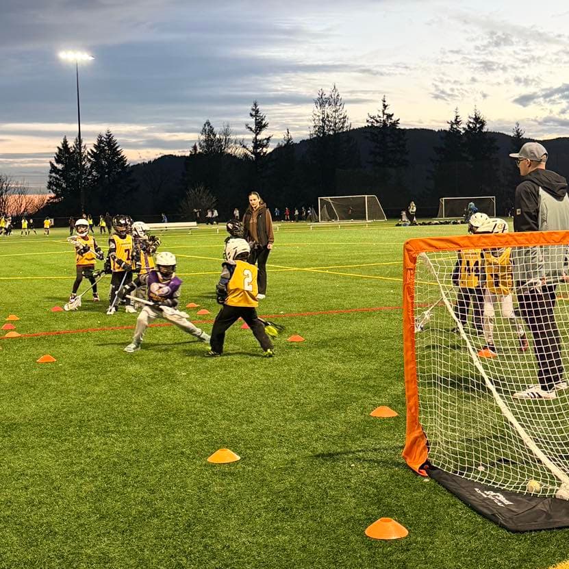 Issaquah K2 players practicing stick skills and dodging near a small goal.
